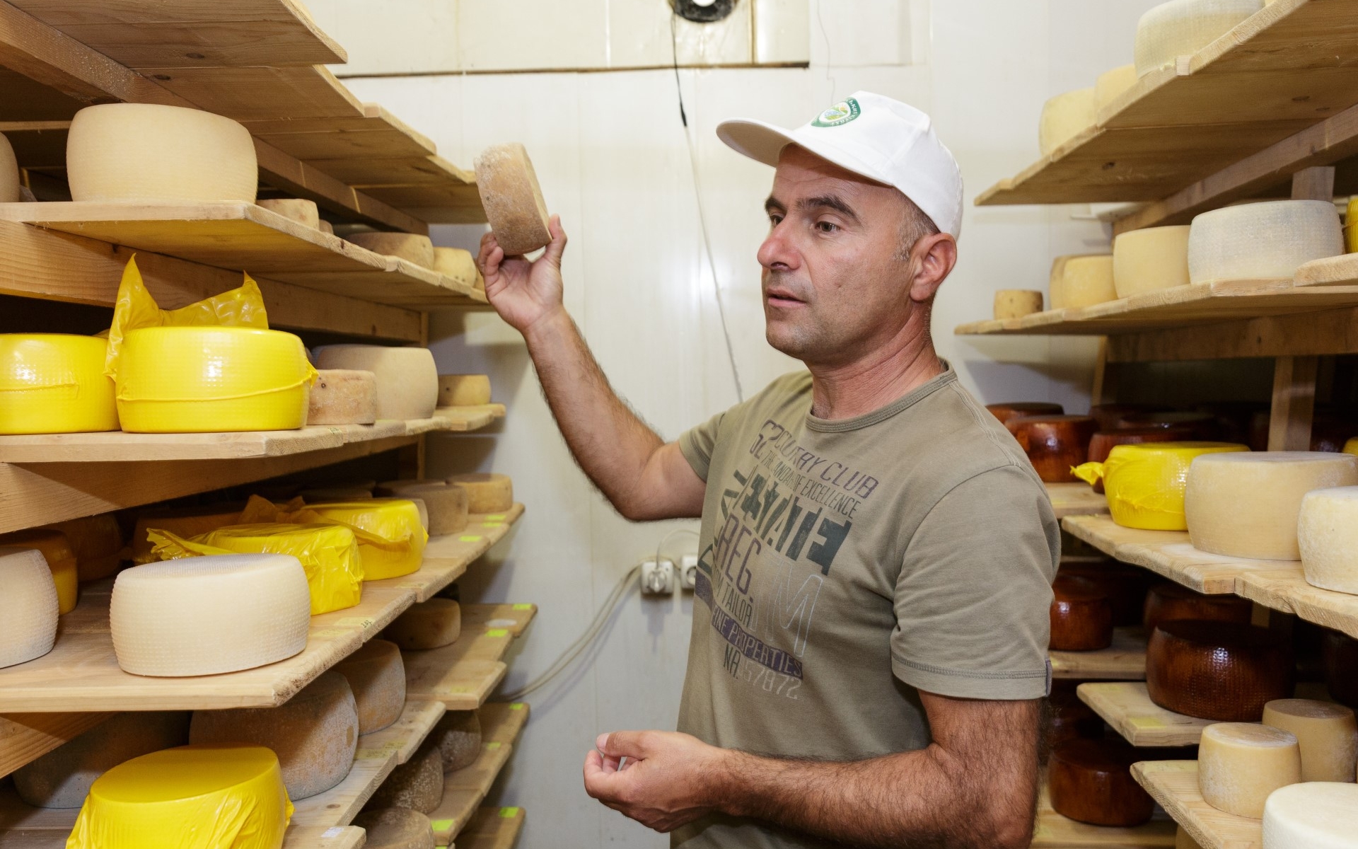 A man stands in his cheese storage room.