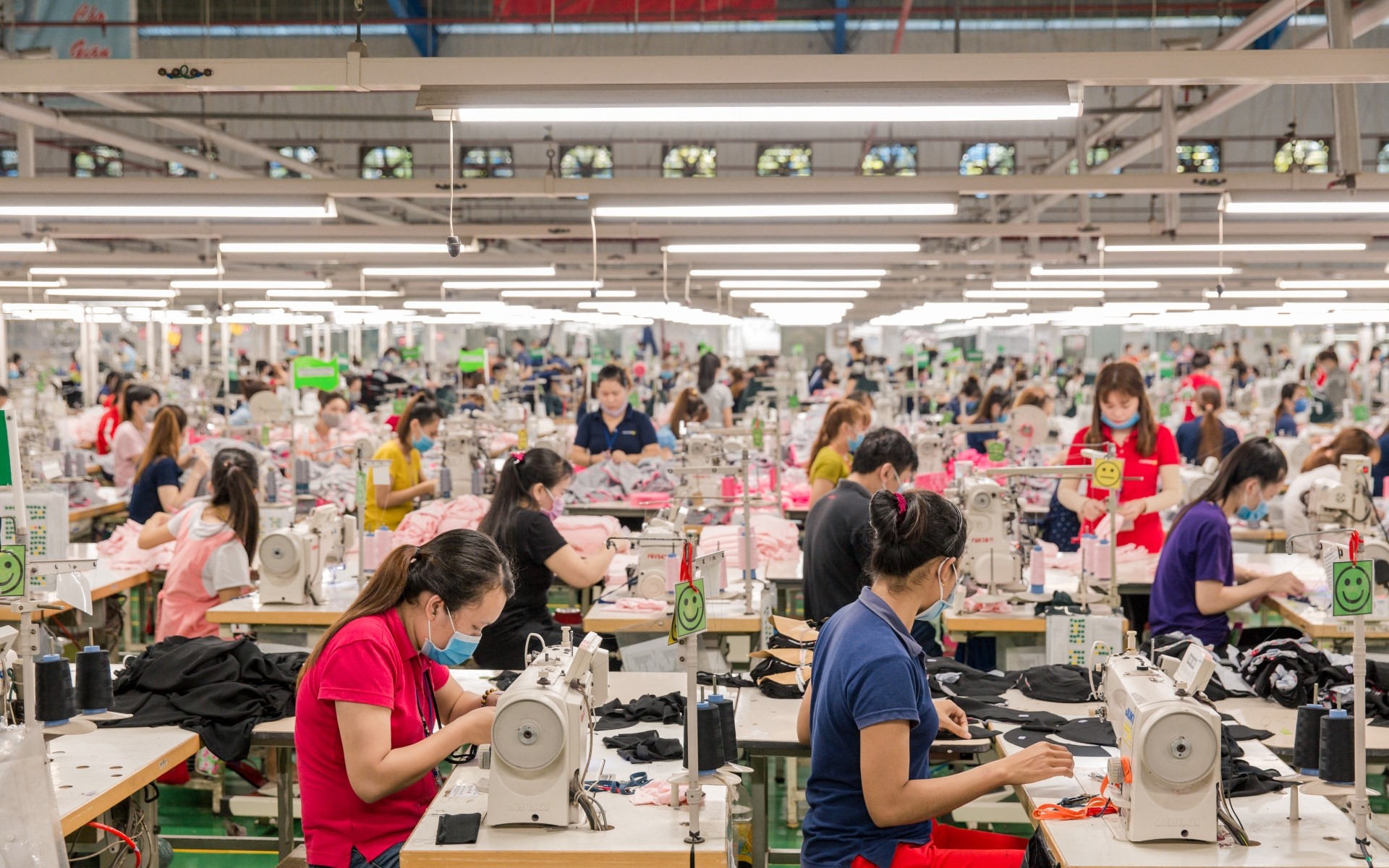 Women at their workstations in a large textile factory. 
