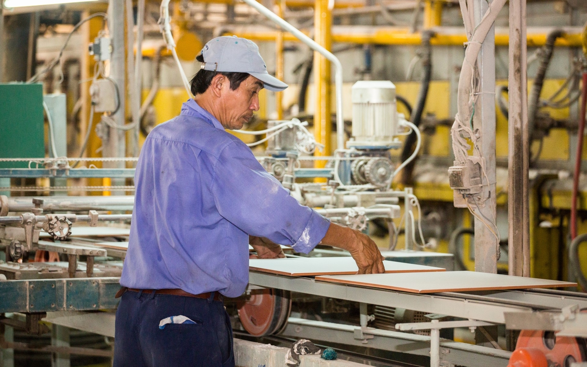 A man processes a ceramic plate in a factory. 
