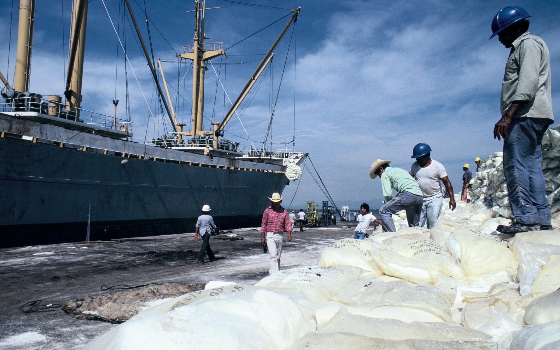 Men load goods onto a merchant vessel in a port. 